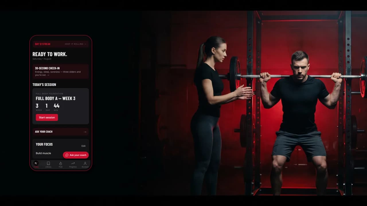 Two people in a gym between sets, looking together at a phone one of them is holding.